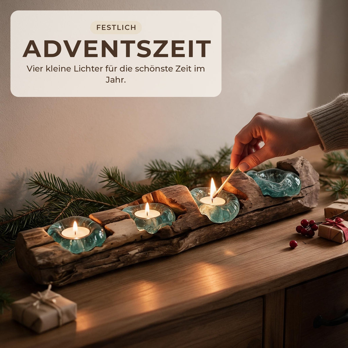 Hand zündet ein Teelicht im Teelichthalter aus Wurzelholz an, Adventsdeko mit Tannenzweigen und kleinen Geschenken