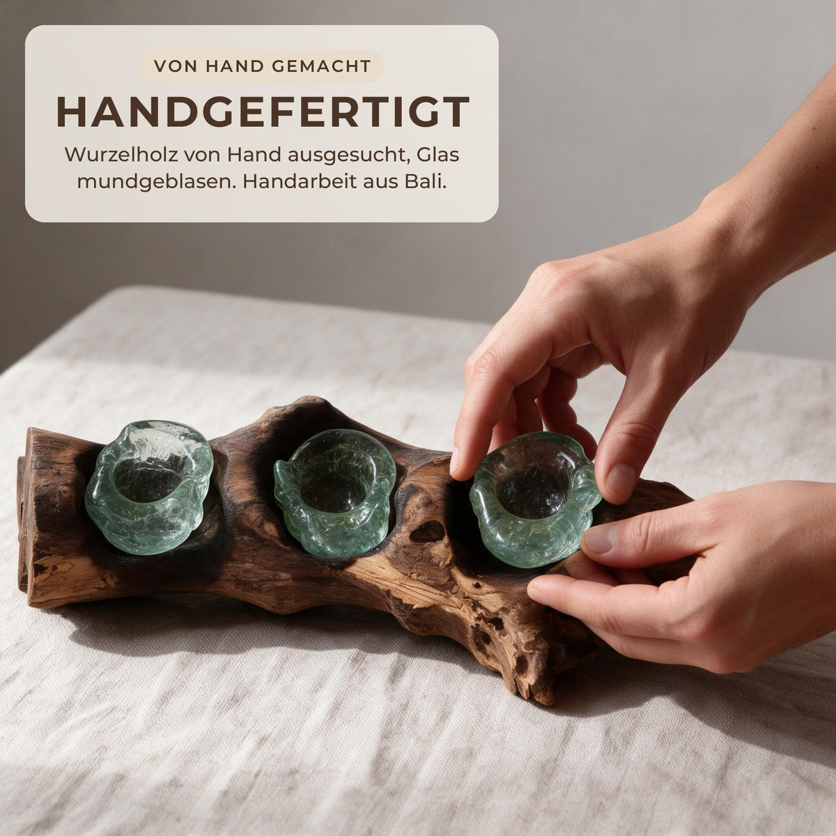 Hände setzen eine mundgeblasene Glasmulde in das Wurzelholz ein – Handarbeit aus Bali
