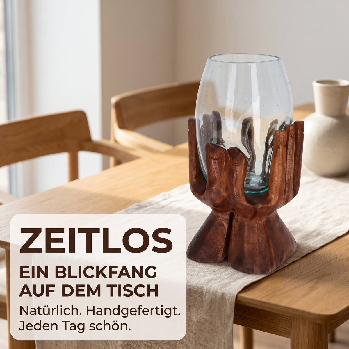 Holzhand aus Suarholz mit hohem Glas als Tischdeko auf einem Esstisch aus Holz mit Leinenläufer, bei Tageslicht.