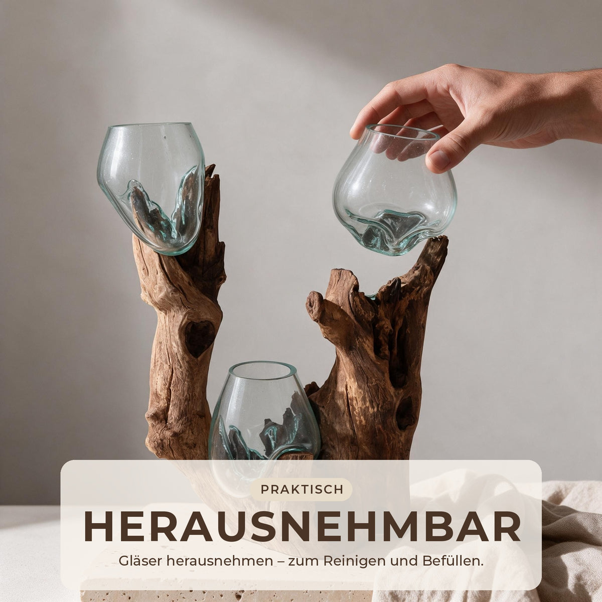 Hand hebt ein Glas aus der Wurzelholz-Skulptur – die drei Gläser sind herausnehmbar