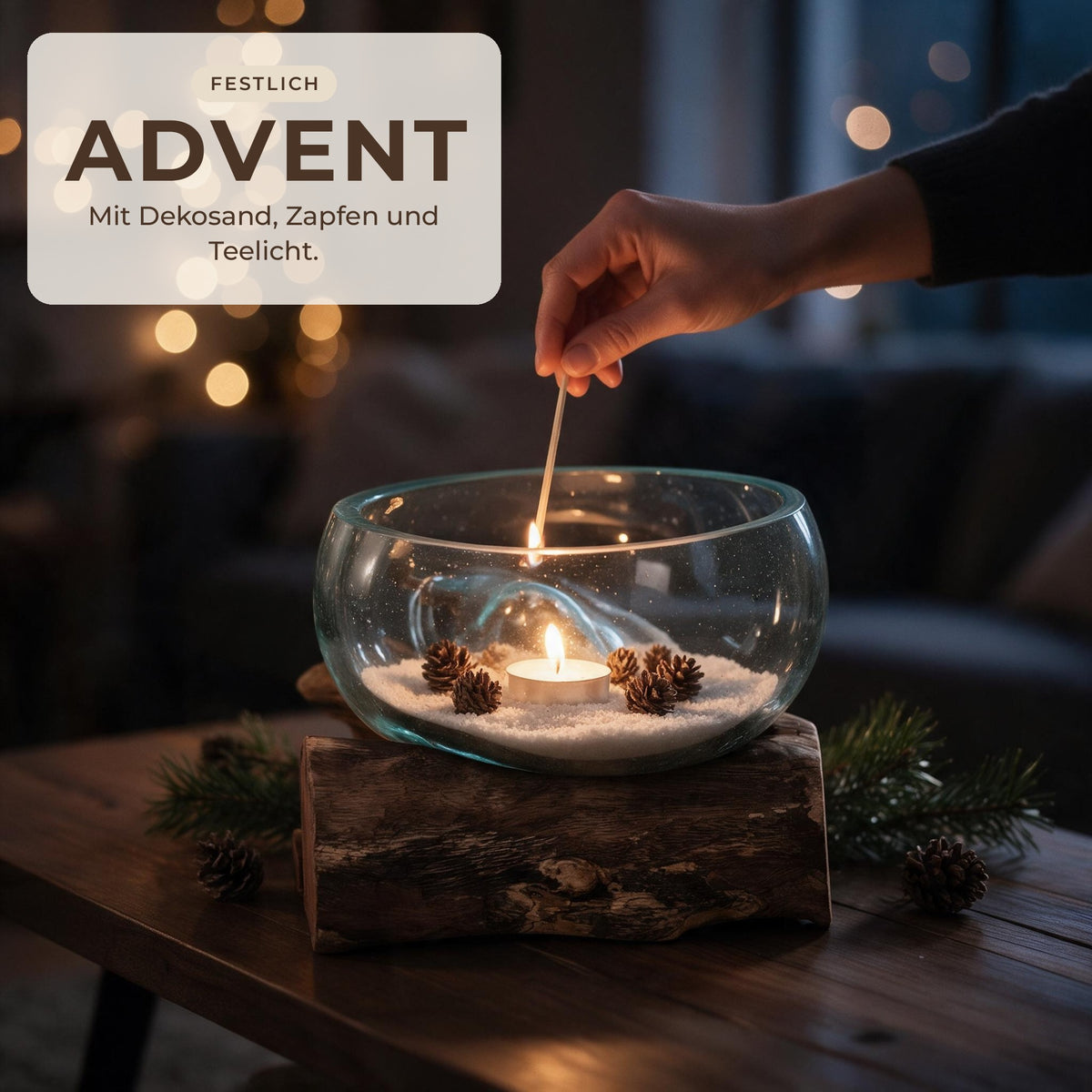 Glasschale auf Wurzelholz mit Dekosand, Zapfen und Teelicht in der Adventszeit, Hand zündet das Teelicht an
