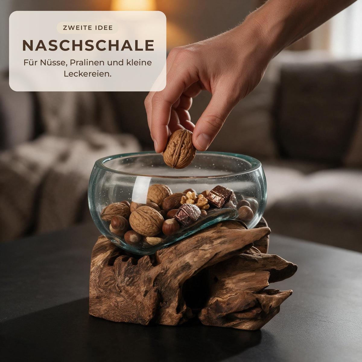 Glasschale auf Wurzelholz als Naschschale mit Nüssen und Pralinen, Hand nimmt eine Walnuss