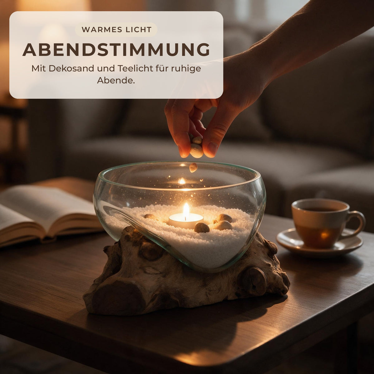 Glasschale auf Wurzelholz mit Dekosand und brennendem Teelicht am Abend auf dem Couchtisch
