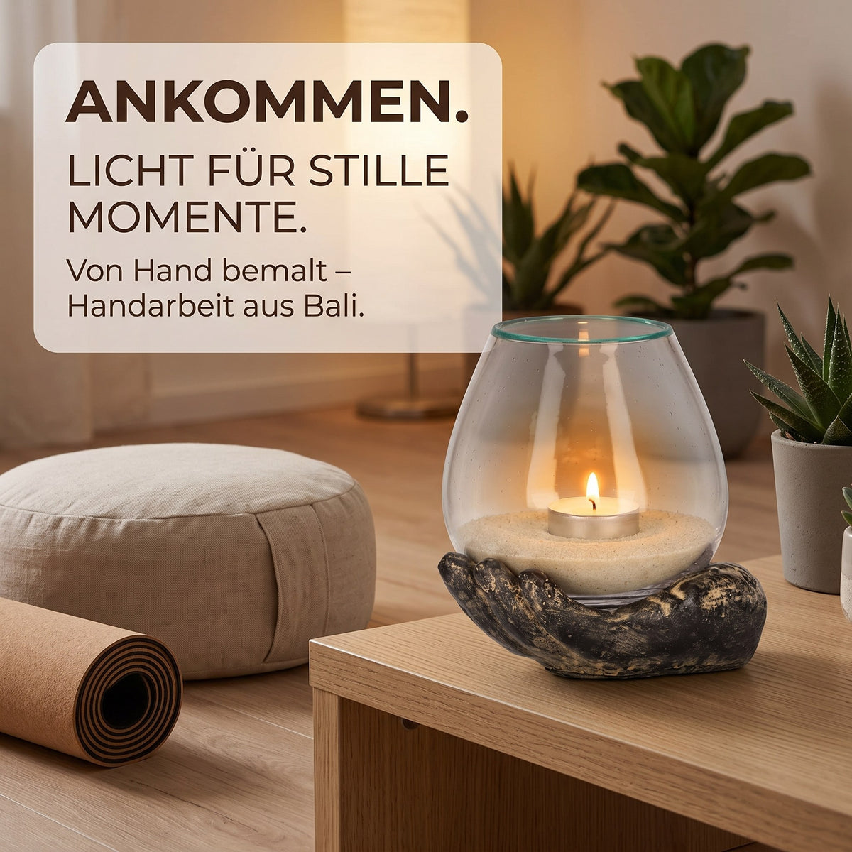 Spirituelle Deko: Hand mit Glas Grau-Sand in der Meditationsecke mit Yogamatte